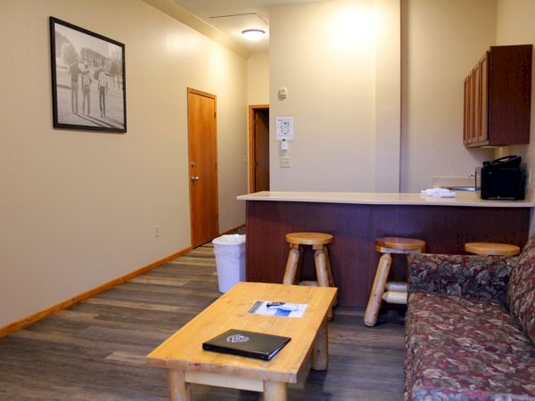 A cozy room with a couch, coffee table, kitchenette, and bar stools.