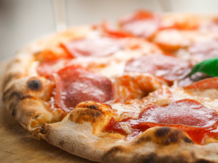 A pepperoni pizza with a golden crust and melted cheese, set on a wooden surface.