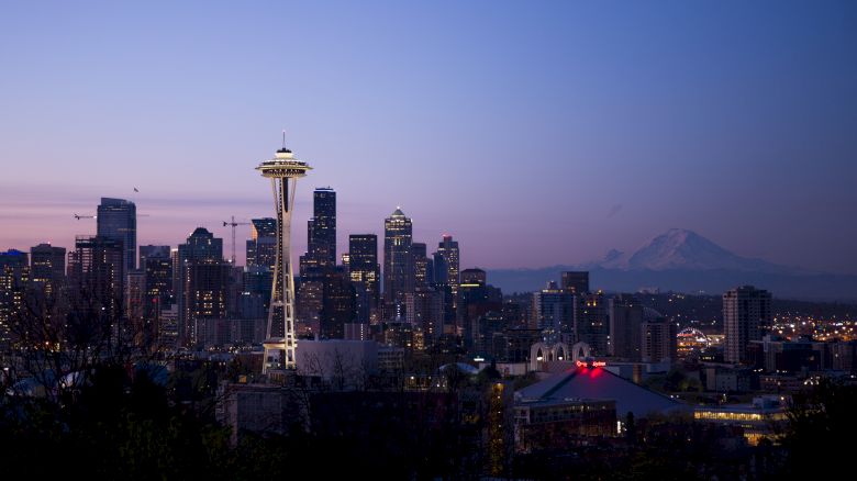 A twilight view of the Seattle skyline with the Space Needle prominently featured and Mount Rainier visible in the background.