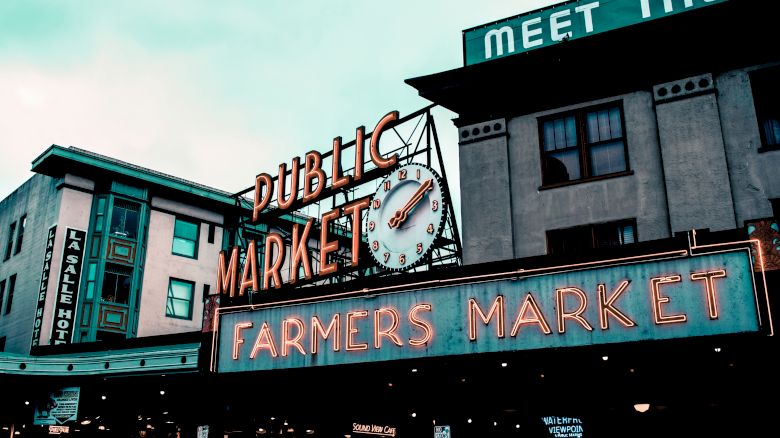 This image features the iconic neon signs at the entrance of Seattle's Pike Place Market, including "Public Market" and "Farmers Market".